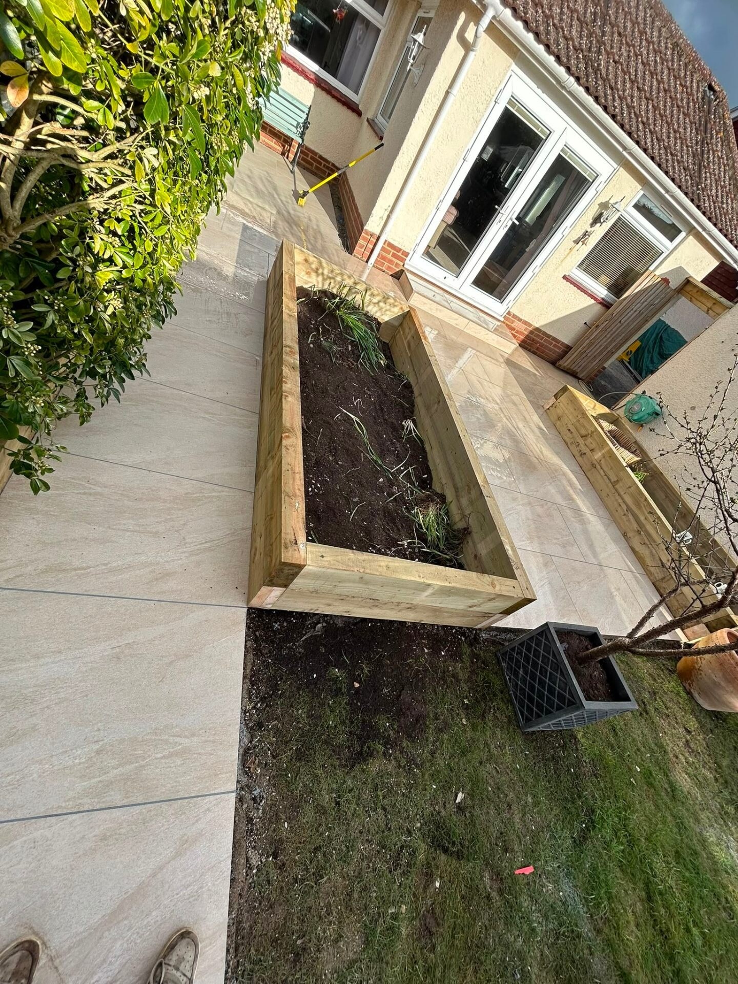 Porcelain patio with timber raised planters at the rear of a coastal home.