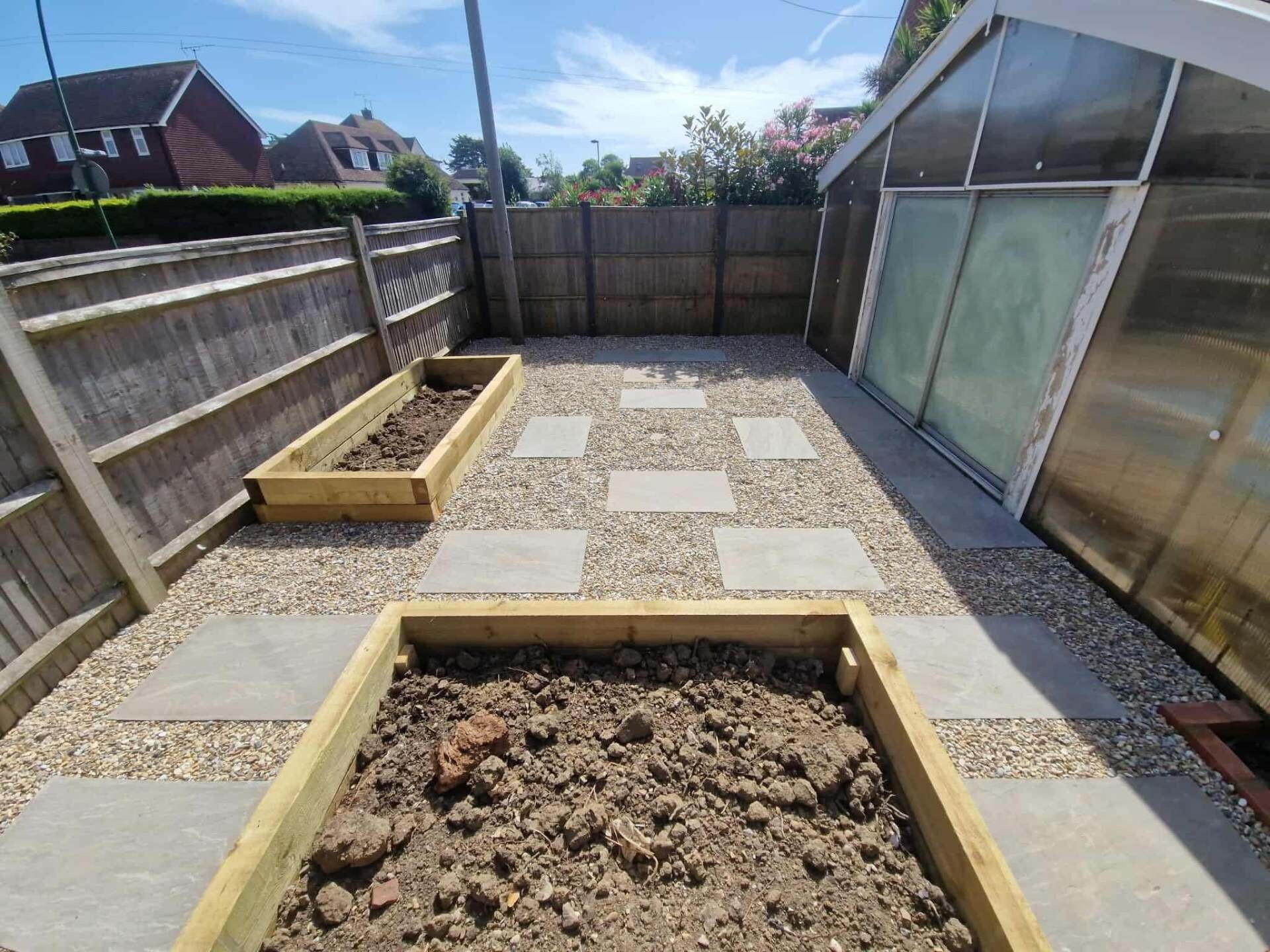Light porcelain patio with checkerboard layout and timber raised beds beside a conservatory.
